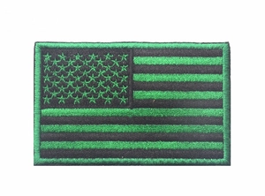 Close-up of black and green US flag patch with detailed embroidery and border stitching