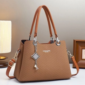Brown leather handbag with woven texture, dual handles and decorative silver pendant