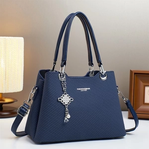 Detailed close-up of dark blue textured leather handbag with pearl and knot charms
