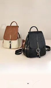 Detail showing pebbled leather texture, gold smile pendant, and WANT YOU strap on the backpack