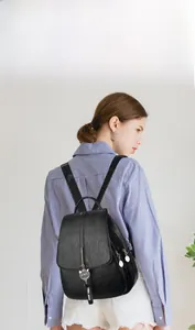 Detail of black leather backpack with cat charm and multiple zipper compartments