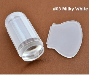 Detail view of milky white silicone nail stamper with transparent scraper set on leather surface
