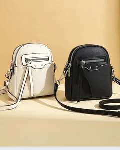 Close-up of pebble leather mini crossbody bags in black and beige with tassel details