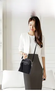 Detailed view of black motorcycle mini crossbody bag featuring silver studs on a model