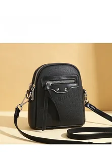 Detail showing litchi grain leather texture and silver rivets on the small crossbody bag