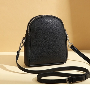 Close-up of black litchi texture phone bag with dual silver zippers and curved design