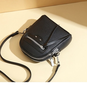 Detail view of black litchi pattern leather crossbody bag with dual zipper compartments