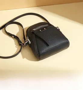 Detail view of black litchi grain leather crossbody bag with moto style metal studs
