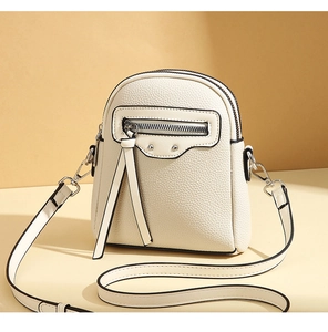 Detail view of cream mini crossbody bag showing lychee grain leather and silver rivets