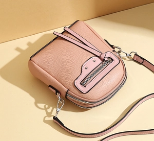 Detailed shot of pink lychee leather phone bag with silver zippers and rivets