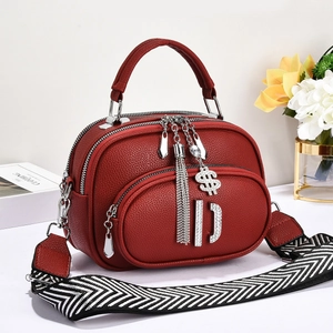 Red lychee pattern leather shoulder bag with wide strap and metallic pendants on white base