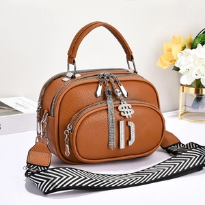 Detail of brown lychee texture leather bag with silver charms and geometric wide strap