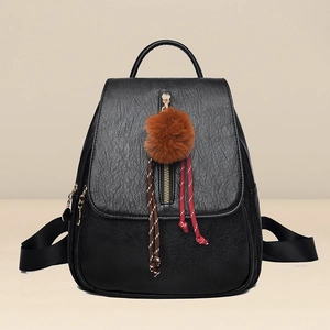 Minimalist black leather backpack for women with vertical zipper and brown pompom charm