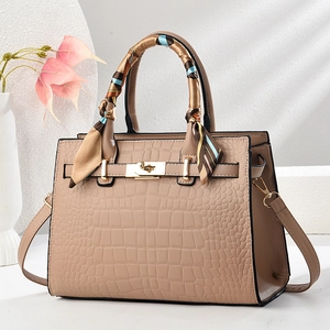 Detail of light brown croc-embossed tote bag with golden twist lock and printed scarf
