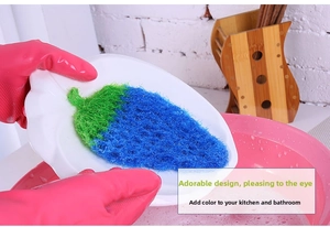 Detail of strawberry-shaped dish scrubber cleaning a plate with fiber material