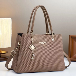 Détail du sac bandoulière marron tressé avec nœud doré et bandoulière en cuir