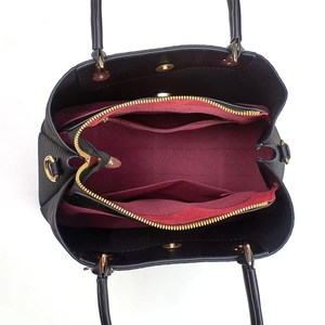 Détail de l'intérieur du sac à bandoulière noir avec doublure bordeaux et zip doré brillant