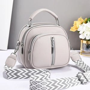 Détail du sac bandoulière gris clair en cuir grainé avec sa large sangle tissée