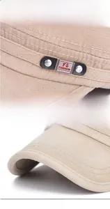 Detail of khaki military flat cap showing metal logo buckle and twill cotton fabric texture