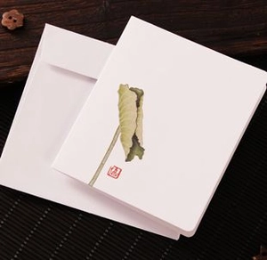 Close-up of Chinese style lotus pattern greeting card with envelope on bamboo mat