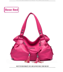 Detail of rose red lychee grain leather handbag with woven handle and tassel accents