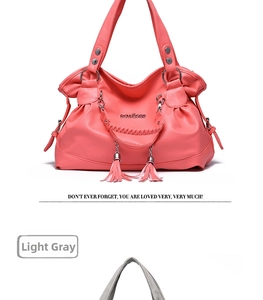 Detail of pink faux leather handbag with braided handle, tassel charm and metal rings
