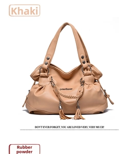 Detail view of khaki faux leather handbag featuring dual handles and fringe tassels