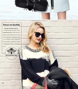 Detail of black leather tote bag with tassel charm and stylish red shoulder strap accent