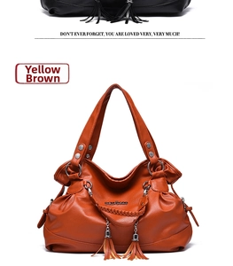 Detail shot of yellow-brown soft leather handbag with tassel charm and woven handle