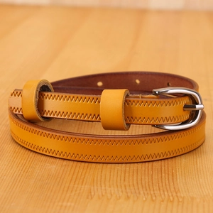 Detail of ginger leather belt with zigzag stitching and silver buckle on wood surface