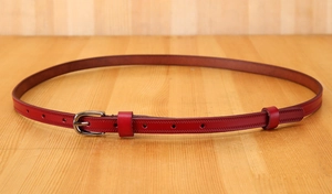 Close-up of red genuine leather thin belt showing neat stitching and silver metal buckle