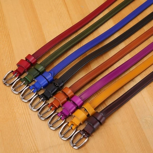 Close-up of colorful leather belts with silver metal buckles on a wood background