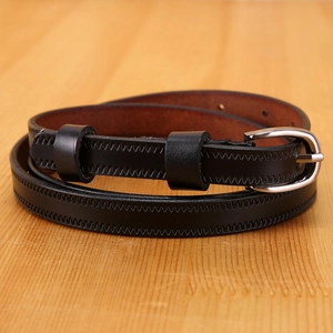 Detail of genuine leather slim belt with silver needle buckle on a wooden background