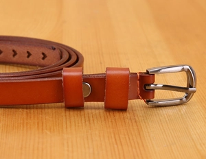 Close-up of brown leather belt with polished silver metal buckle on wood background