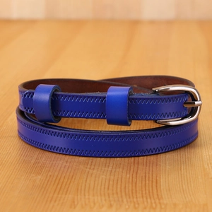 Macro shot of cobalt blue leather belt with textured stitching and silver buckle