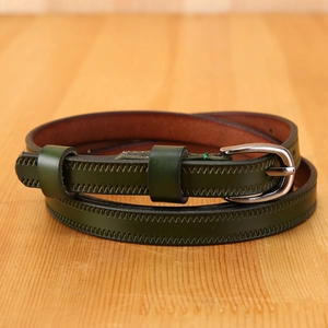 Detail of dark green leather belt with zigzag stitching and silver oval buckle