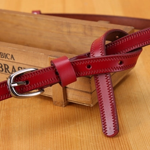 Close-up of wine red leather belt with silver buckle and detailed sawtooth stitching