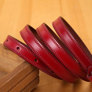 Macro view of dark red leather belt with zigzag stitching details on wooden stand