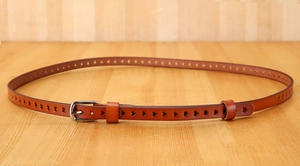 Detail of a slim brown leather belt for women featuring heart-shaped laser-cut perforations
