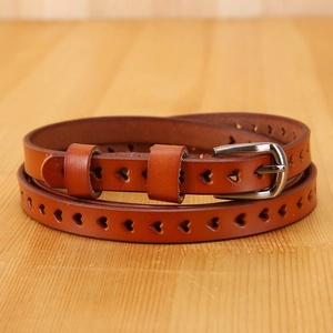 Brown leather belt with heart cut-outs and silver metal buckle on wood background