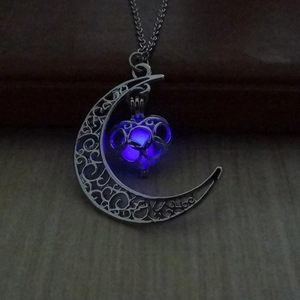 Gros plan du cœur bleu lumineux dans un pendentif de lune argentée creuse
