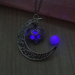 Vue détaillée du pendentif croissant de lune évidé et cage cœur avec perle bleue lumineuse