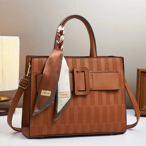 Close-up of brown embossed tote bag with decorative silk scarf and metal buckle detail