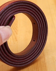Close-up of wine red genuine leather belt showing edge stitching and material thickness
