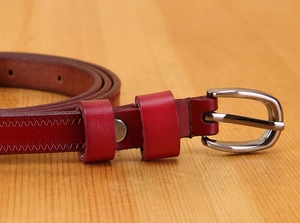 Close-up of a dark red leather skinny belt featuring a silver buckle and fine stitching