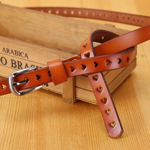 Detail of caramel leather belt with heart-shaped cutouts and silver metal buckle