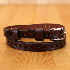 Detail of heart-shaped hollow patterns on dark brown leather belt with silver pin buckle
