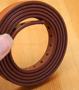 Macro detail of high-quality brown genuine leather belt with natural grain and texture