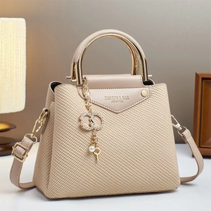 Detail of woven texture beige crossbody bag with gold handle and pearl charms