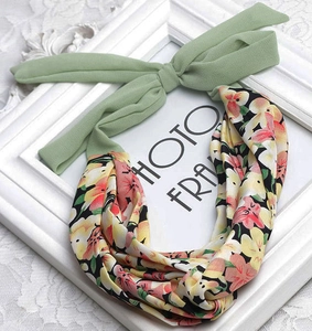 Floral print chiffon headband with a light green ribbon bow on a white lace background